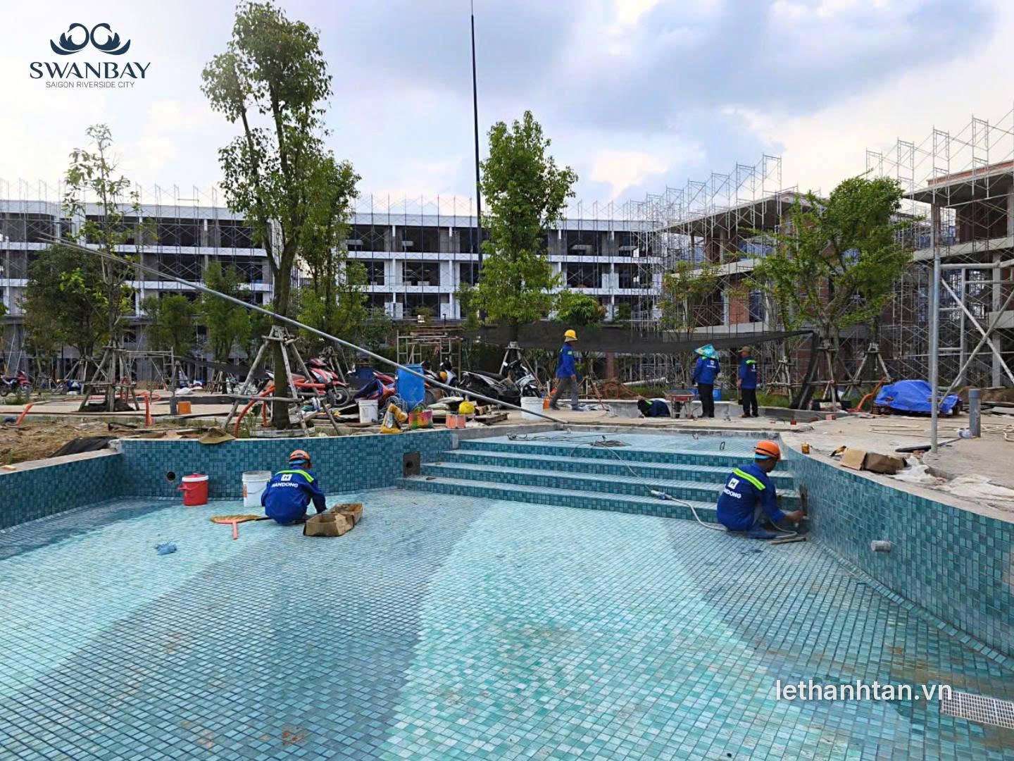 Hồ bơi Oasia Swanbay đang ốp gạch, phía sau là dãy nhà đang hoàn thiện